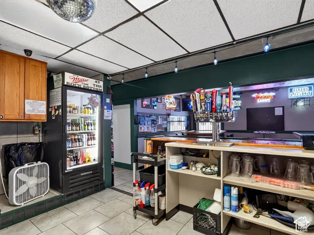 Built-in bar station featuring a multi-tap draft system, solid surface countertop, open cabinetry, and tile flooring