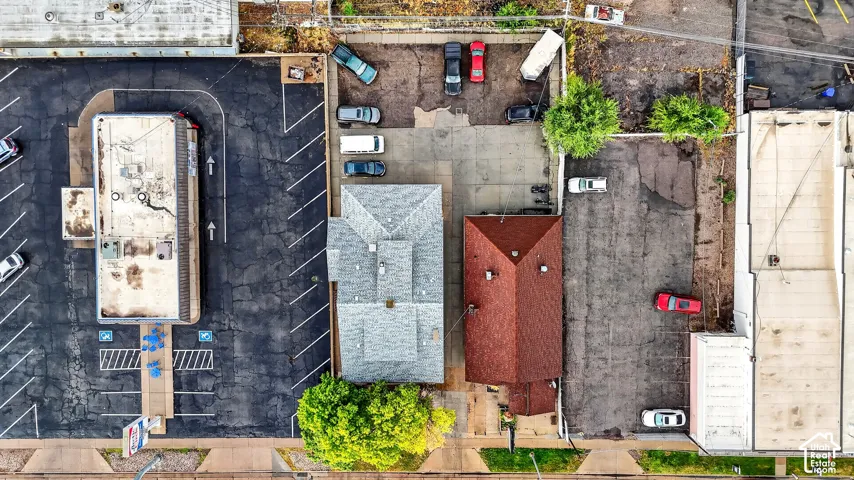Aerial view of the property featuring dual structures, concrete parking areas, and mature trees
