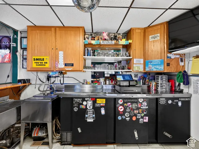 Bar area featuring wood cabinetry, stainless steel sink, under-counter refrigeration units, and open shelving