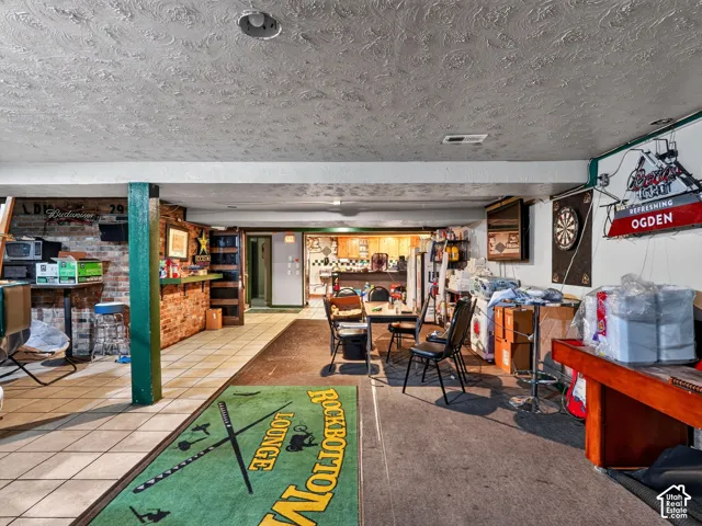 Finished lower level featuring exposed brick masonry, ceramic tile flooring, and a structural support column