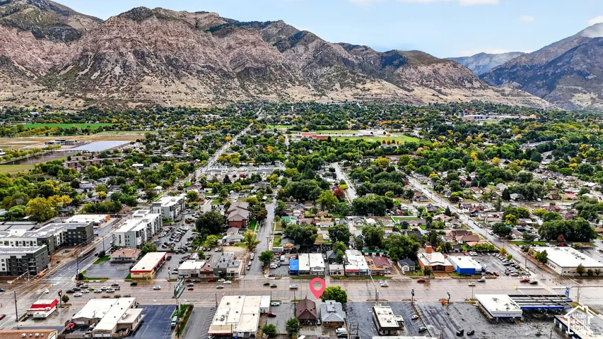 Aerial perspective of the subject property featuring a pitched-roof structure, asphalt parking area, and mountain backdrop