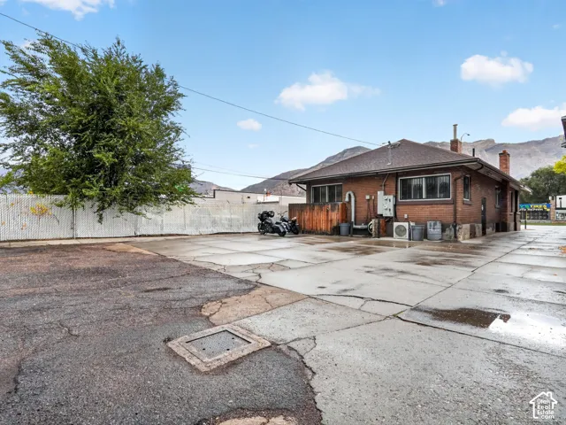 Masonry exterior with brick facade, concrete paved lot, and mountain backdrop
