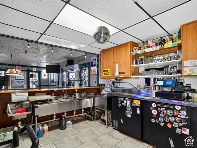 Custom bar area featuring built-in oak cabinetry, stainless steel triple-basin sink, drop ceiling with recessed lighting, and tile flooring