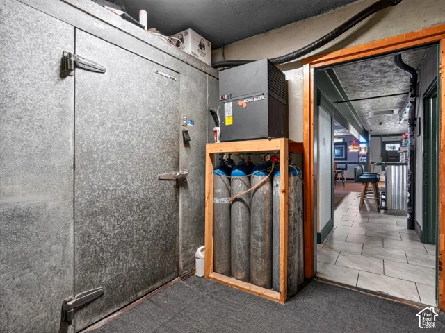 Walk-in refrigeration unit with galvanized metal door, industrial-grade beverage dispensing system, and carbon dioxide tank storage rack