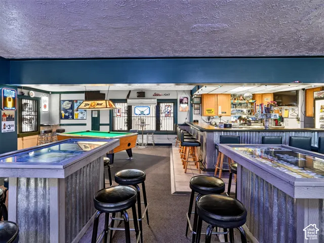 Custom bar area featuring corrugated metal siding, wood-trimmed surfaces, recessed lighting, and built-in cabinetry