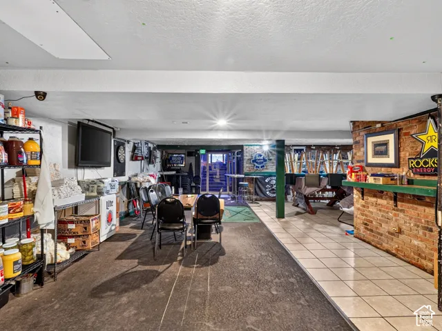 Lower level interior featuring exposed brick wall accents, ceramic tile flooring, and integrated structural support column
