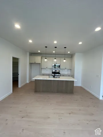 Kitchen featuring a center island, light-finish cabinetry, stone-surface countertops, wood-finish flooring, and recessed ceiling lighting