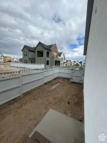 Private side yard featuring a concrete patio pad and white vinyl privacy fencing with an integrated gate