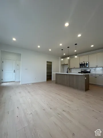 Open-concept interior featuring light wood-finish flooring, recessed lighting, a center island with a stone countertop, shaker-style cabinetry, and pendant lighting