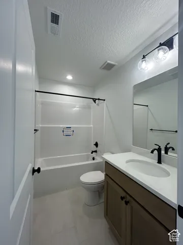 Bathroom featuring a vanity with a light-tone wood finish and a light-colored countertop, an undermount sink with matte black hardware, a shower-tub combination with white surround, and a three-globe vanity light fixture