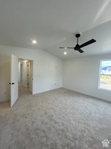 Vaulted ceiling featuring a matte black finish ceiling fan and recessed lighting, neutral carpeting, and a multi-panel door with black hardware