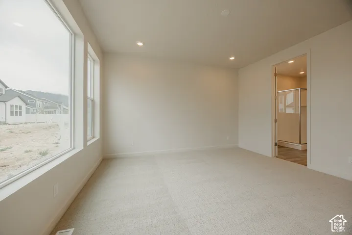 Interior space featuring neutral-toned carpeting, recessed ceiling lighting, and large windows