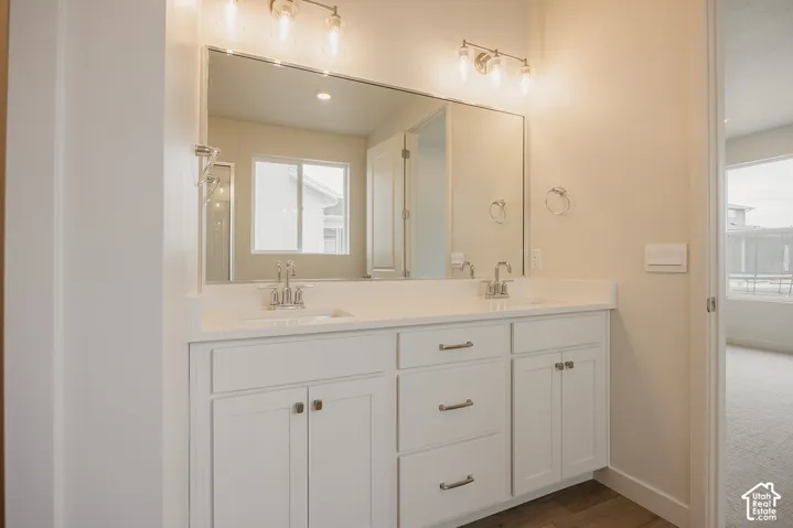 Double vanity with white cabinetry, solid-surface countertop, dual under-mount sinks, chrome hardware, and a full-width vanity mirror with integrated light fixtures
