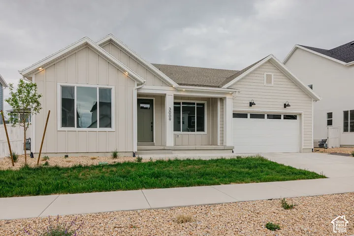 Exterior featuring vertical board-and-batten siding, horizontal lap siding, a covered front porch, two-car garage with windows, and concrete driveway