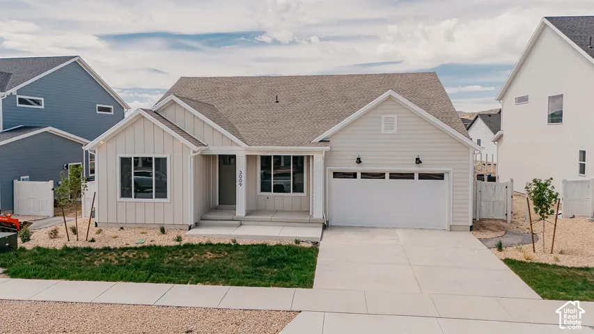 Single-story residence featuring light-toned horizontal lap siding, vertical board-and-batten accents, a two-car garage, and a concrete driveway