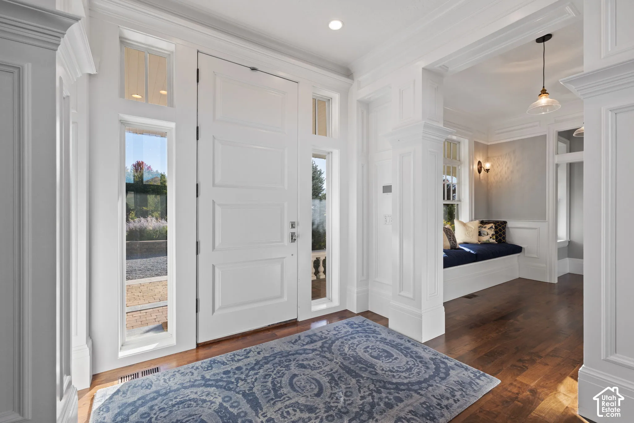 Entryway featuring an oversized paneled door with full-length sidelights, extensive custom wainscoting, wood-finish flooring, a built-in window seat, and recessed lighting