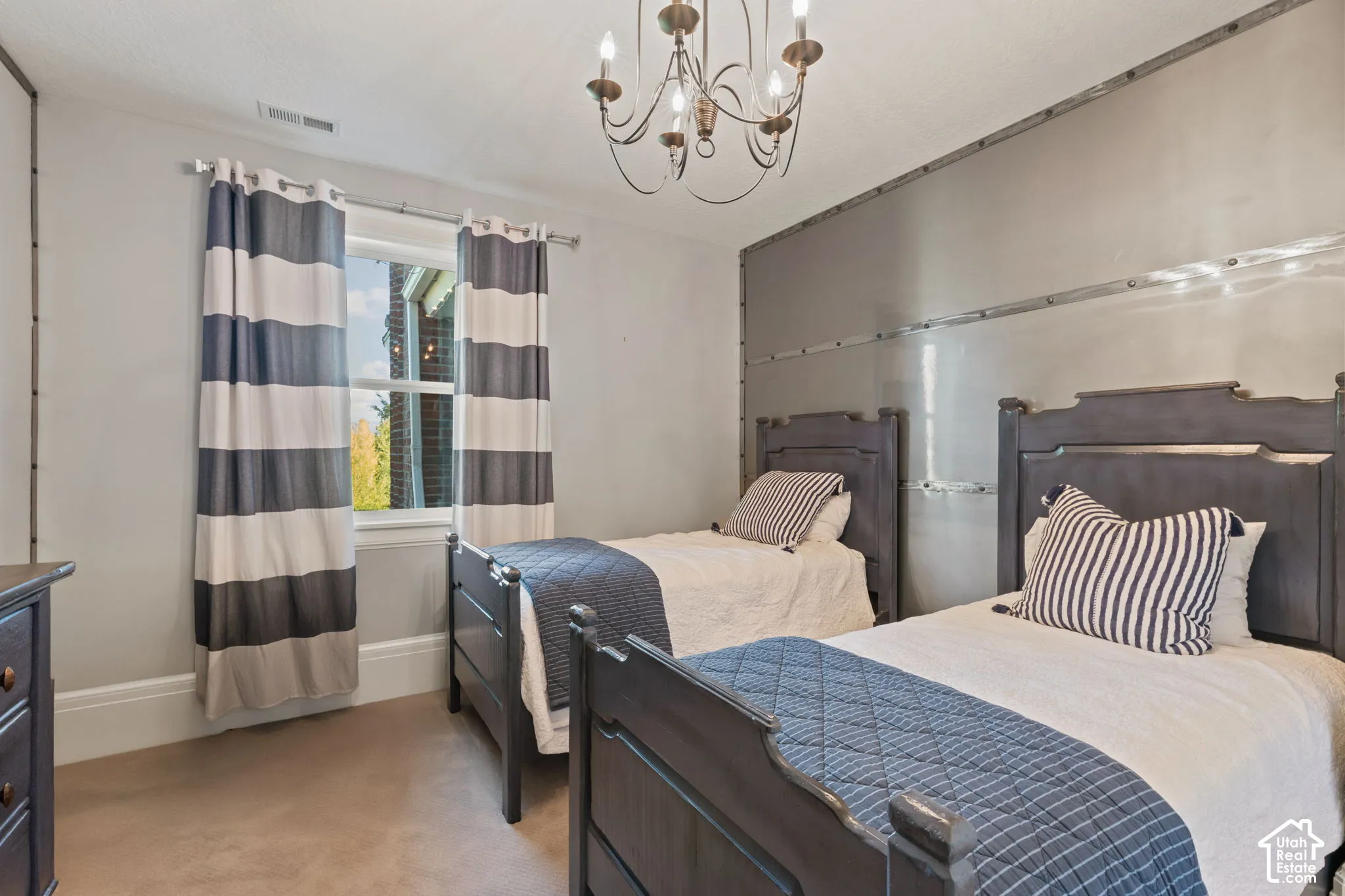 Interior space featuring a metallic-finish accent wall with industrial detailing, an ornate multi-arm chandelier, and wall-to-wall carpeting