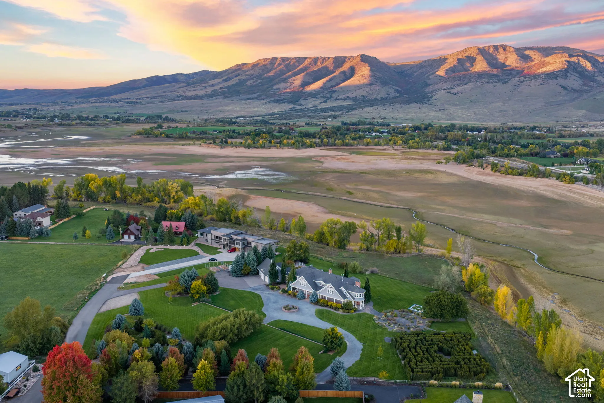 Sprawling estate set on manicured grounds featuring mature landscaping, tree-lined driveway, and multiple residential structures positioned across verdant acreage