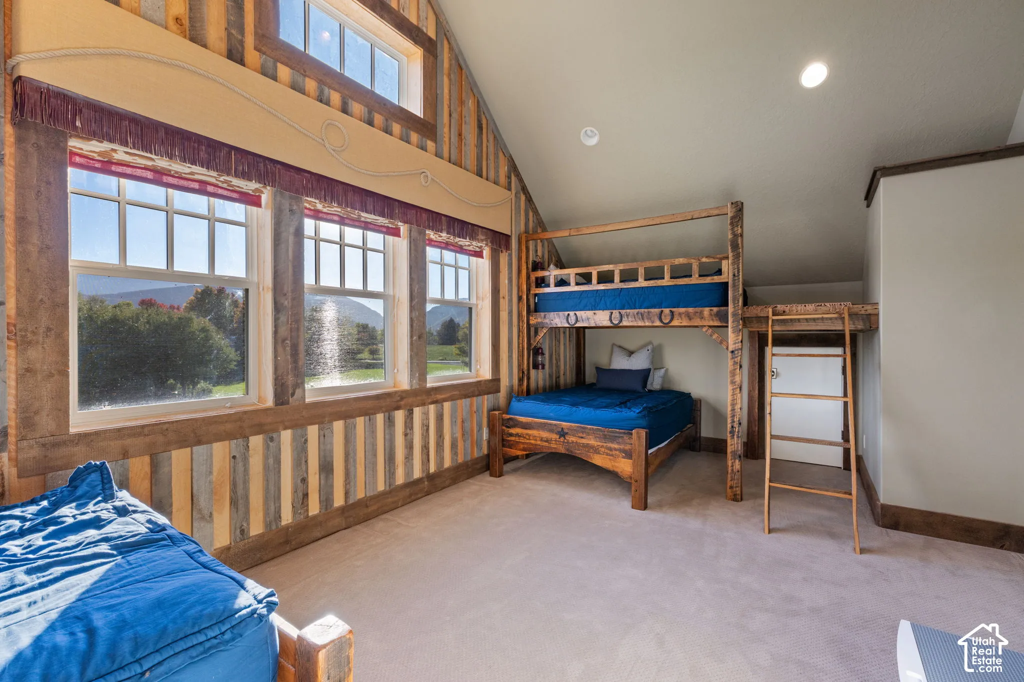 Bunkroom with built-in beds, vaulted ceiling, wood-plank wall paneling, multi-pane windows with mountain scenery