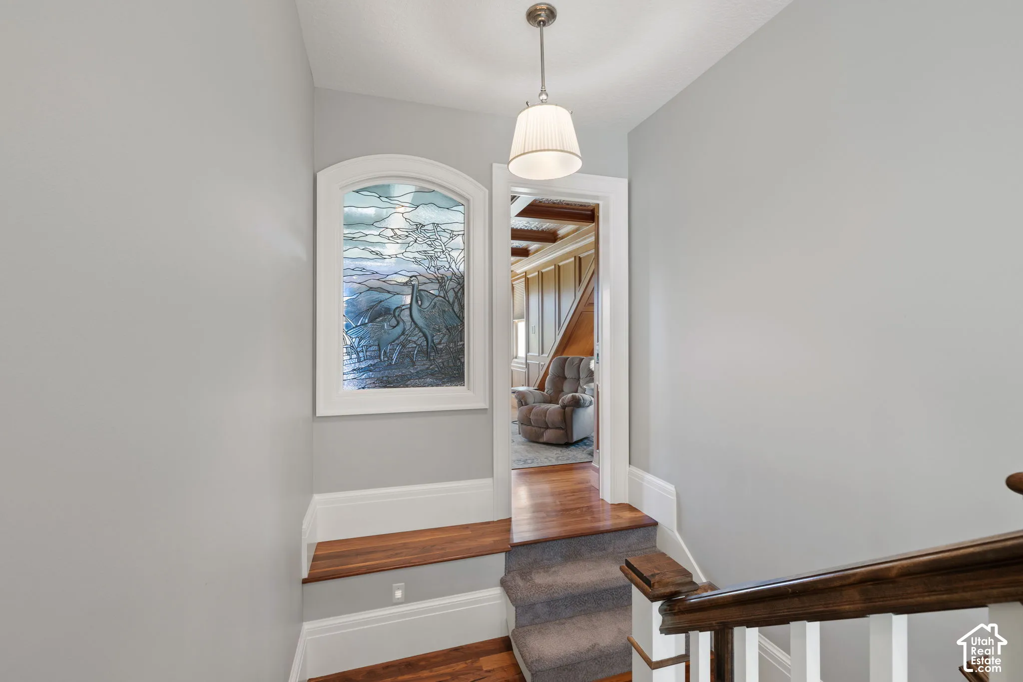 Arched stained-glass window, wood-finish stair tread, pendant lighting, and wood handrail with white balusters