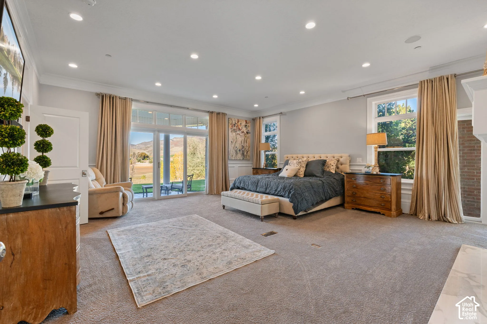 Spacious bedroom featuring recessed lighting, crown molding, expansive glass sliding doors, and a brick-accented fireplace surround