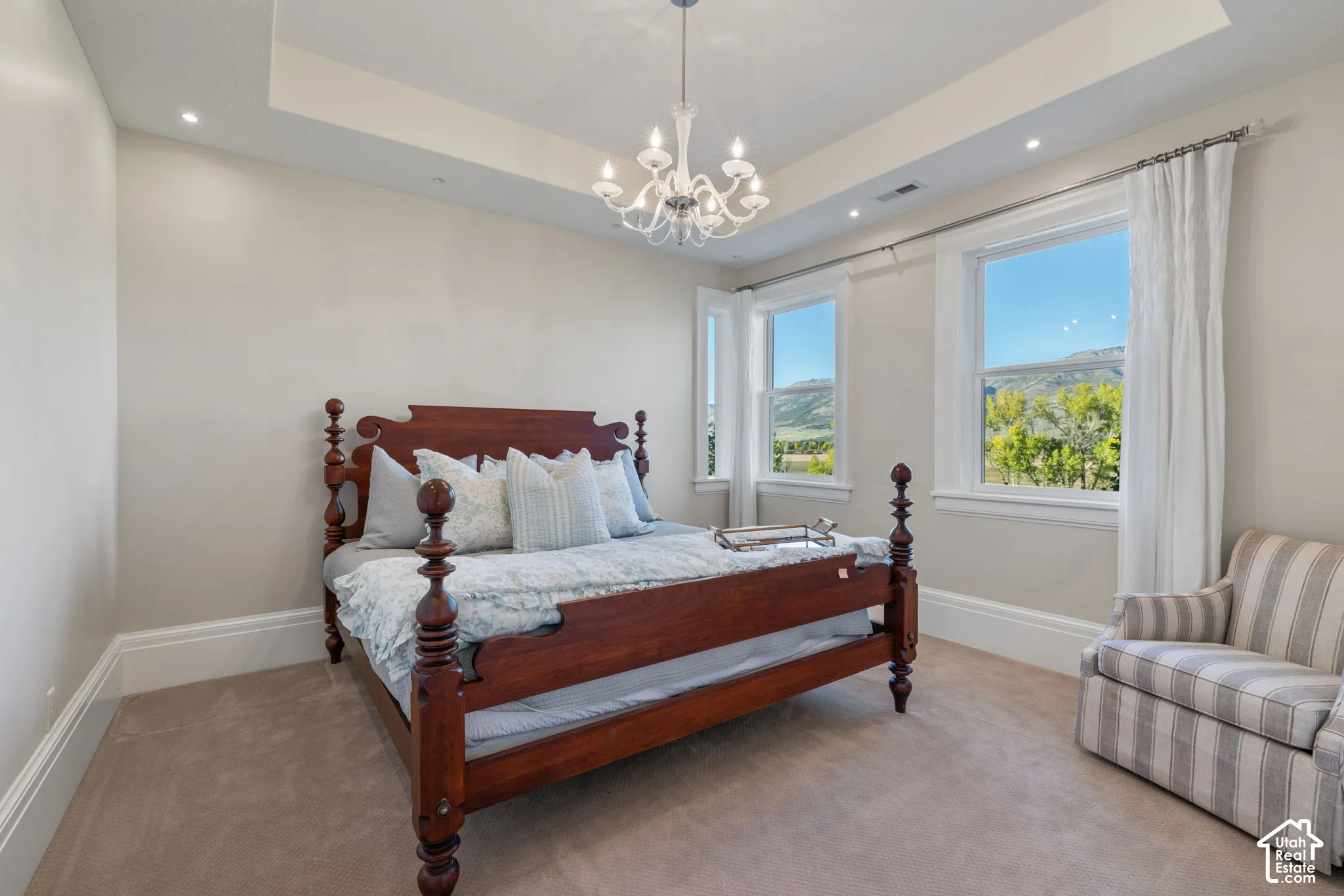 Tray ceiling with recessed lighting, traditional chandelier, and large windows with mountain landscape scenery