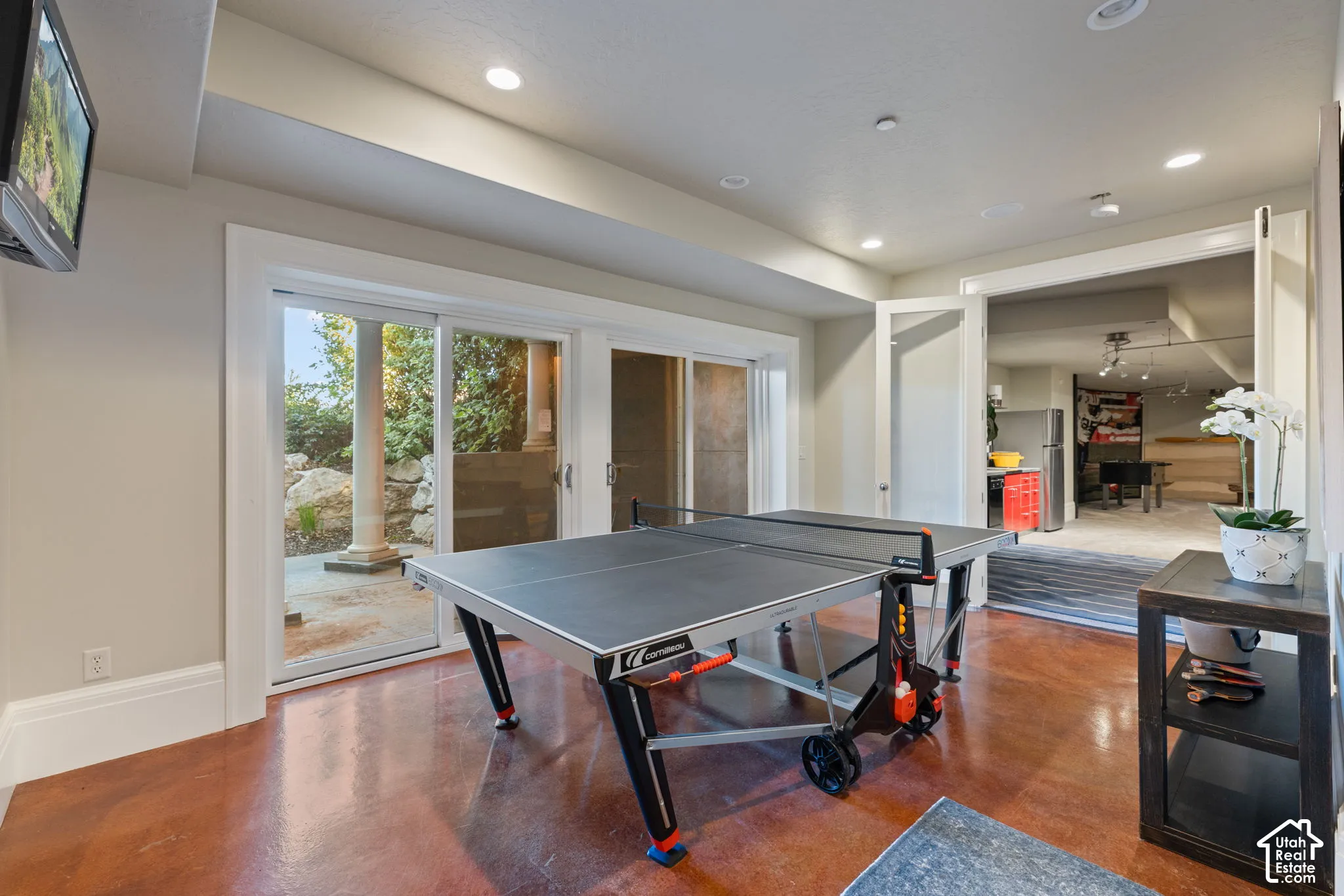 Room featuring stained concrete flooring, recessed lighting, and large sliding glass doors opening to a covered patio with stone pillar supports