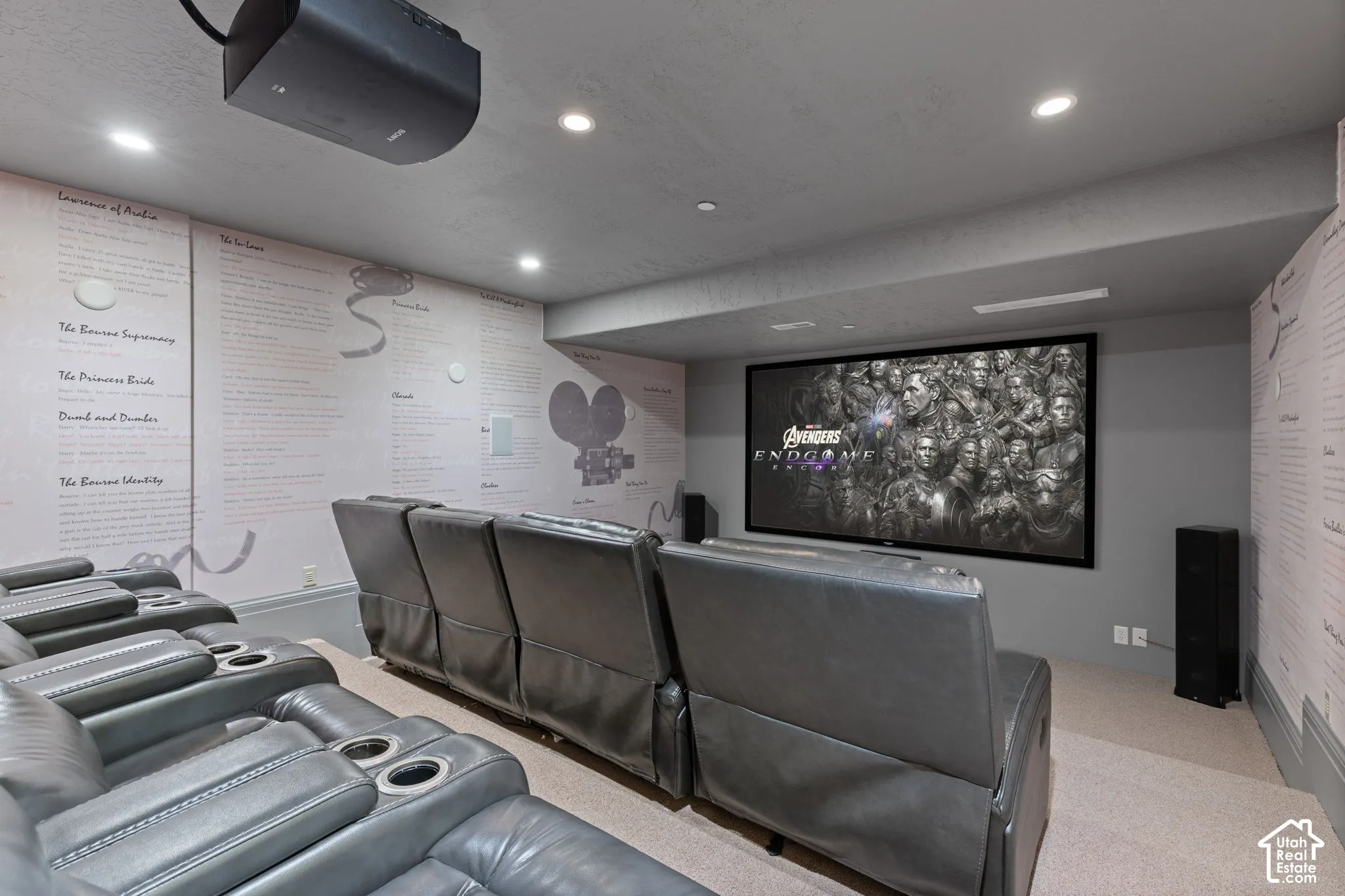 Dedicated media room featuring a wall-mounted projection screen, ceiling-mounted projector, recessed lighting, and custom graphic wallpaper