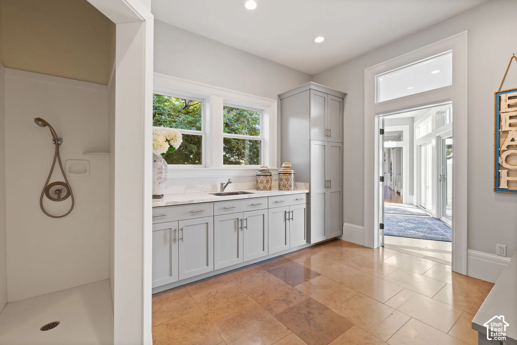 Custom cabinetry with integrated storage, stone countertop with undermount sink, ceramic tile flooring, recessed lighting, and built-in shower stall