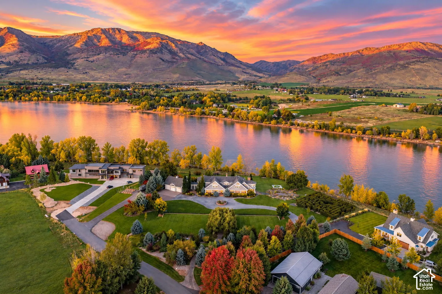 Aerial perspective featuring expansive waterfront acreage, mature landscaping, paved circular driveways, and mountain range backdrop. Accurate AI generated depiction of the reservoir at full capacity. Lake is currently drained for pipeline repair.