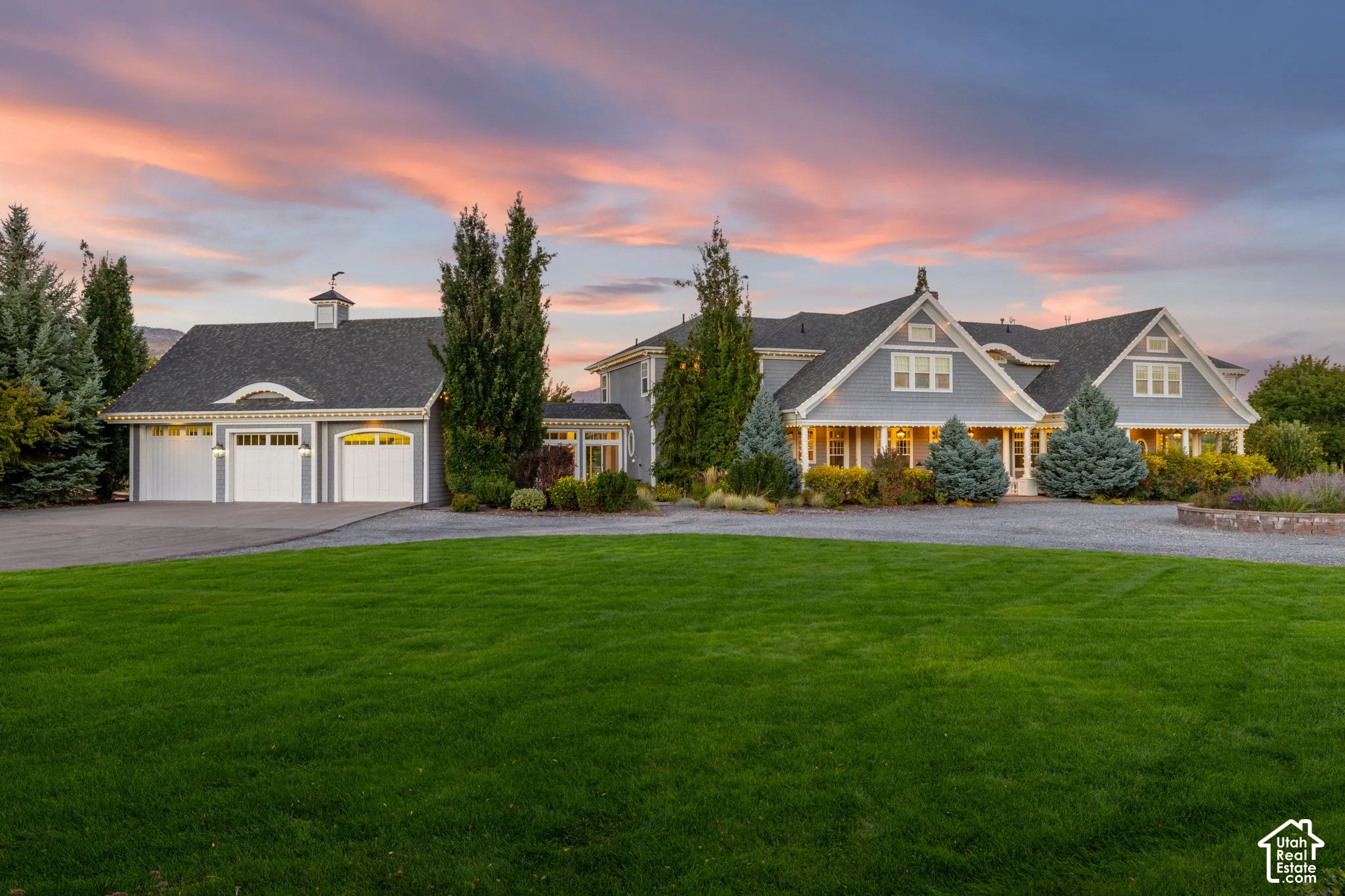 Multi-gabled exterior with shingle siding, covered front porch, three-car garage with cupola, and gravel driveway