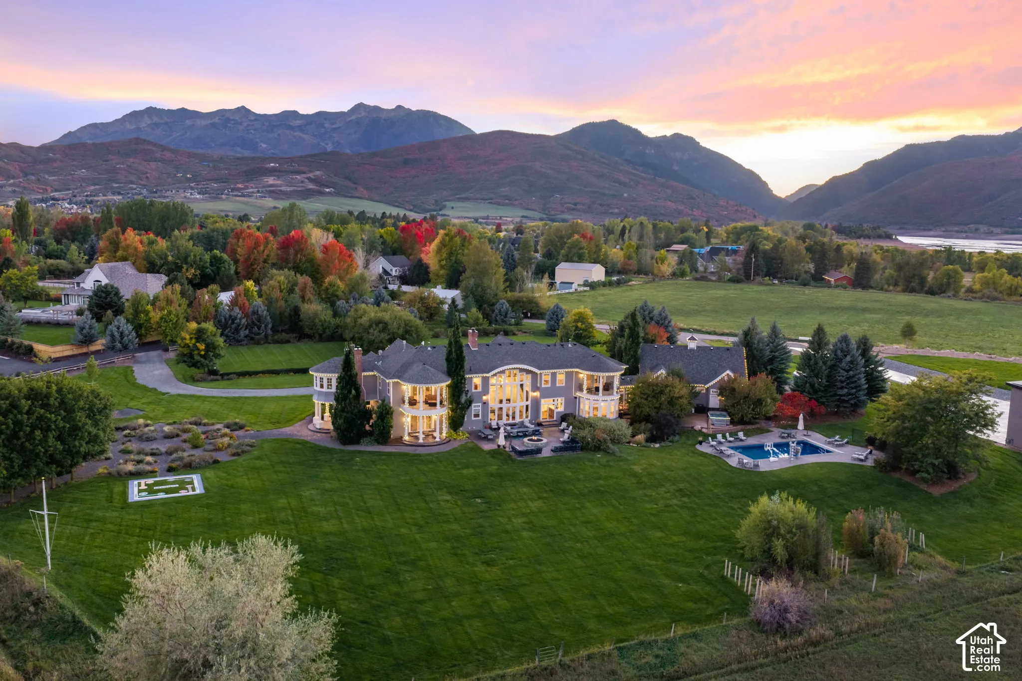 Expansive property featuring multi-level rear covered balconies, a private swimming pool, formal hardscaped garden beds, and mountain scenery