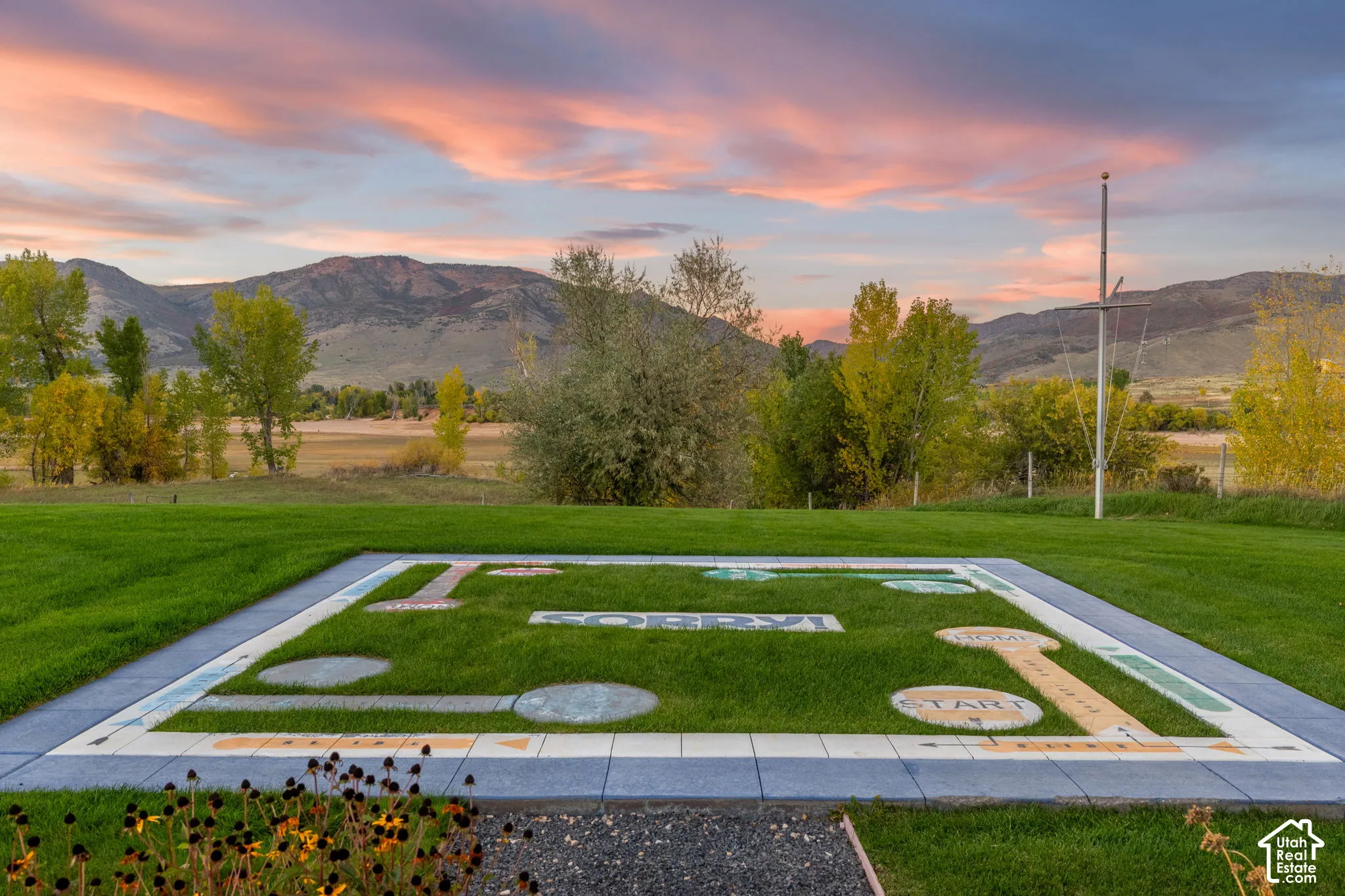Expansive lawn featuring a custom-integrated hardscape game board, perimeter stone paver border, and mountain horizon