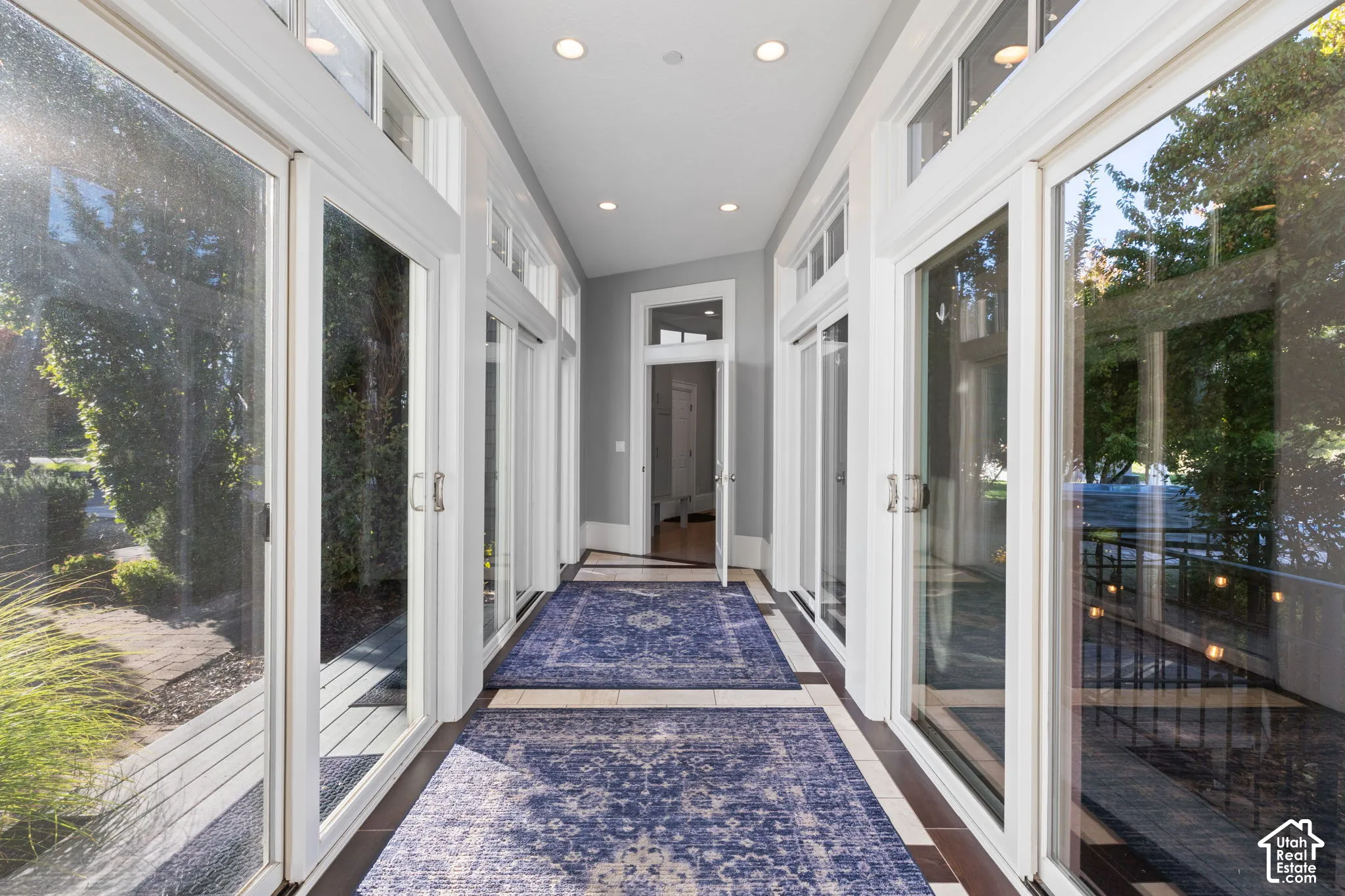 Sunroom featuring expansive sliding glass doors, transom windows, neutral-toned tile flooring, and recessed ceiling lighting