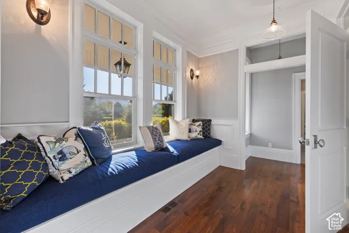 Built-in window seating with white cabinetry, wood-finish flooring, multi-pane windows, wall-mounted light fixtures, and white wainscoting