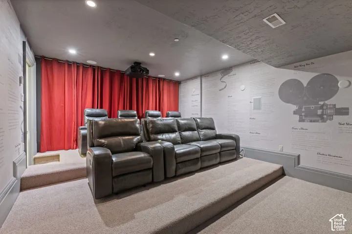Dedicated media room featuring tiered flooring, recessed lighting, ceiling-mounted projection equipment, and custom wall murals