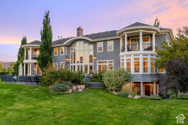 Multi-level exterior featuring floor-to-ceiling windows, dual wraparound balconies with decorative iron railings, and tiered landscaping