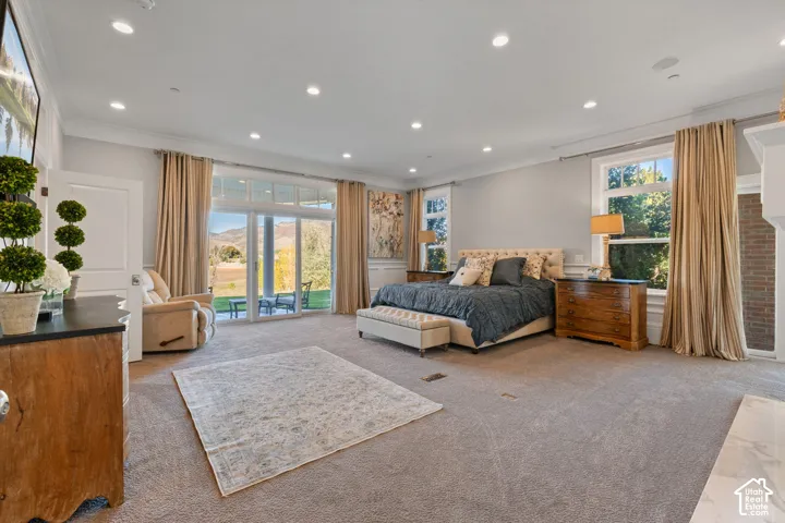 Spacious bedroom featuring recessed lighting, crown molding, expansive glass sliding doors, and a brick-accented fireplace surround