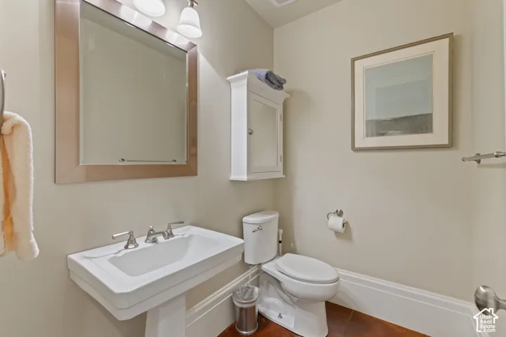 White porcelain pedestal sink with metallic widespread faucet, wall-mounted mirrored medicine cabinet, and wall-mounted storage cabinet