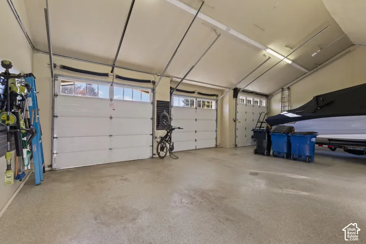 Spacious two-car garage with overhead doors, epoxy flooring, and integrated storage solutions including wall-mounted bike racks and overhead shelving
