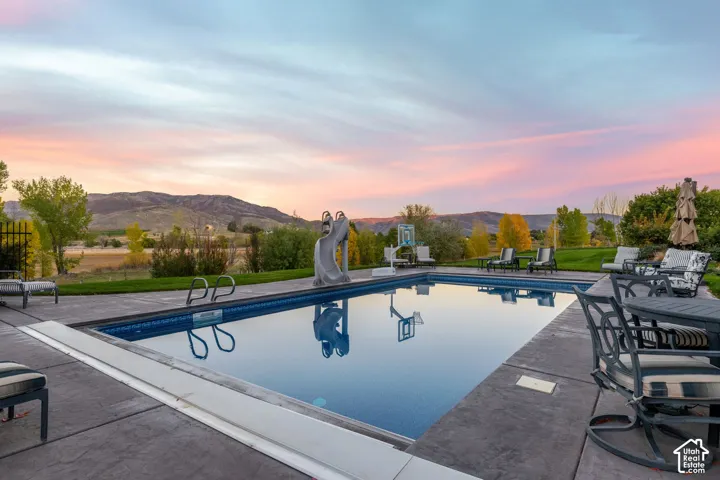Inground swimming pool with slide, stamped concrete decking, and mountain backdrop