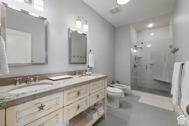Double vanity with dual under-mount sinks and stone countertops, glass-enclosed walk-in shower with integrated bench seating, and ceramic tile flooring