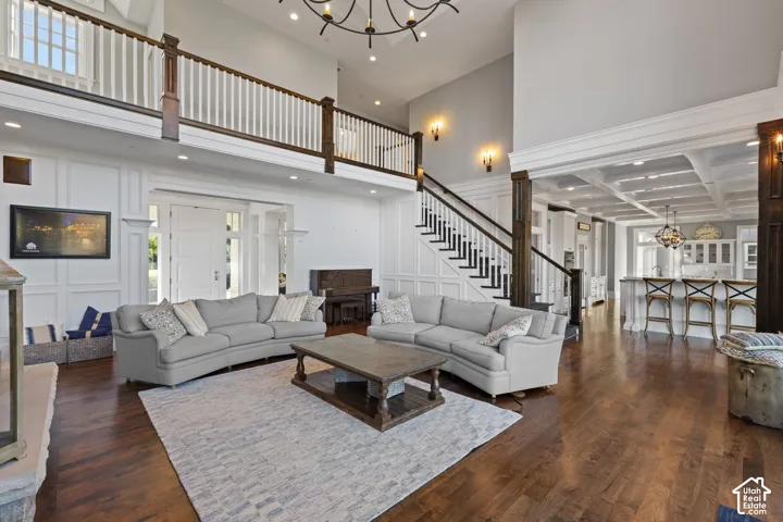 Double-height foyer featuring extensive wainscoting, wood-finish flooring, a grand staircase with dark wood railings, and a coffered ceiling