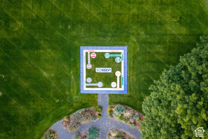 Expansive lawn featuring a built-in, ground-level game board, crushed stone pathways, and mature trees