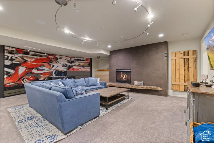 Fireplace featuring a large-format tile surround, integrated hearth, and recessed firebox, complemented by circular track lighting and wood-paneled wall accents