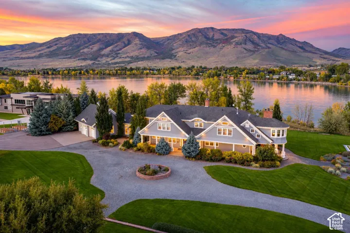 Waterfront residence featuring mountain scenery, multi-gabled roofline, lap siding, circular gravel motor court, and manicured lawn. Accurate AI generated depiction of the reservoir at full capacity. Currently drained for pipeline repair.