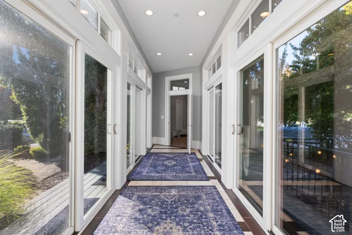 Sunroom featuring expansive sliding glass doors, transom windows, neutral-toned tile flooring, and recessed ceiling lighting
