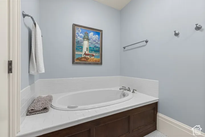 Built-in soaking tub with white subway tile surround, dark wood-finished cabinetry, wall-mounted brushed metal hardware, and dual chrome towel bars