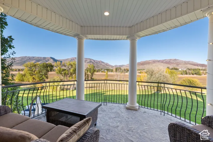 Covered balcony featuring stone flooring, classic architectural columns, and metal railing overlooking mountainous terrain and Pineview Reservoir.