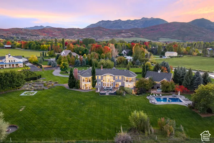 Expansive estate featuring multi-level outdoor balconies, a private swimming pool, professional landscaping, and extensive acreage against a mountain backdrop